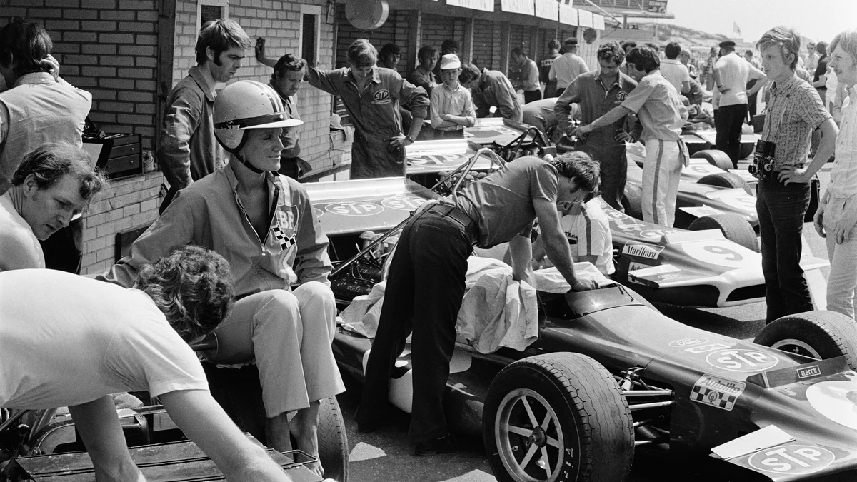 1970s pit lane team personnel wearing retro racing jacket apparel and sponsor windbreakers